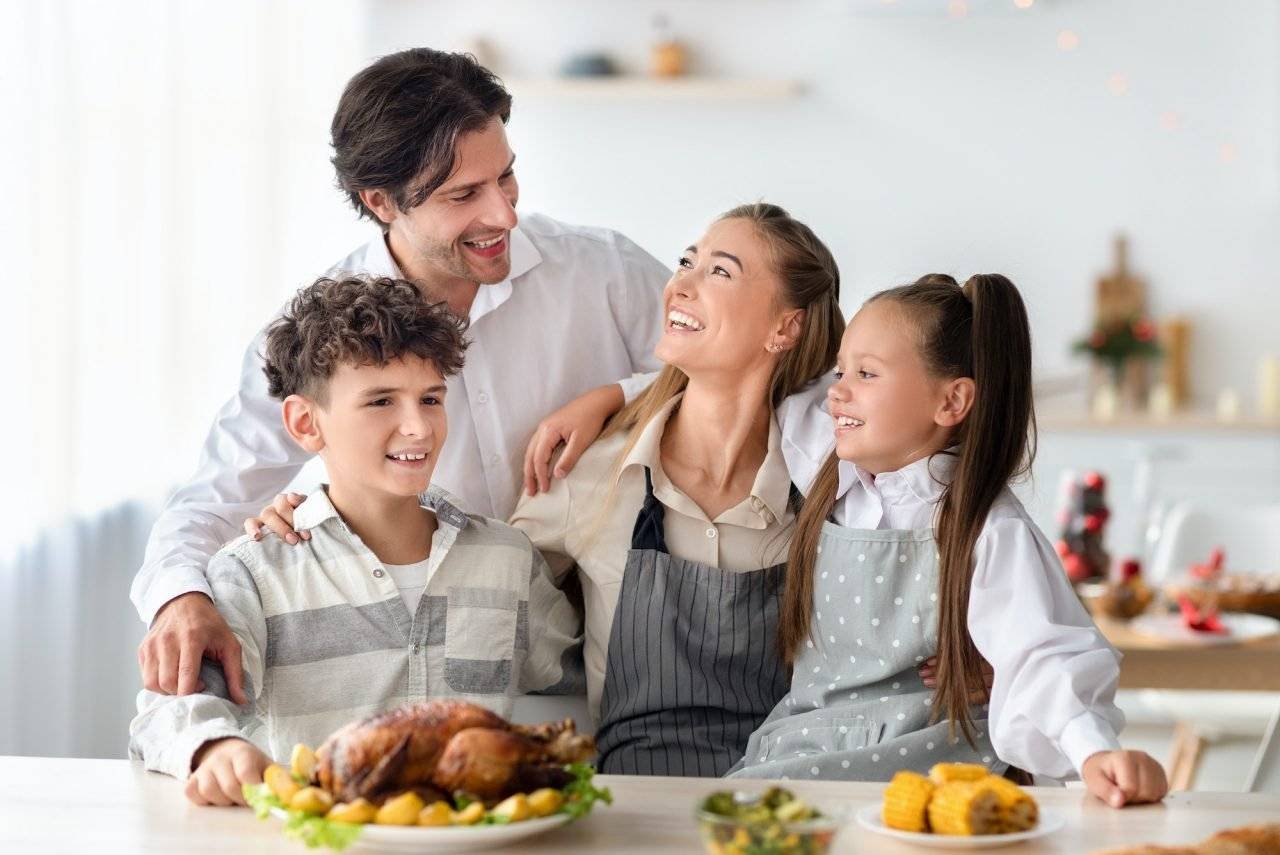 happy family with parents and kids posing together in kitchen preparing meal for christmas or